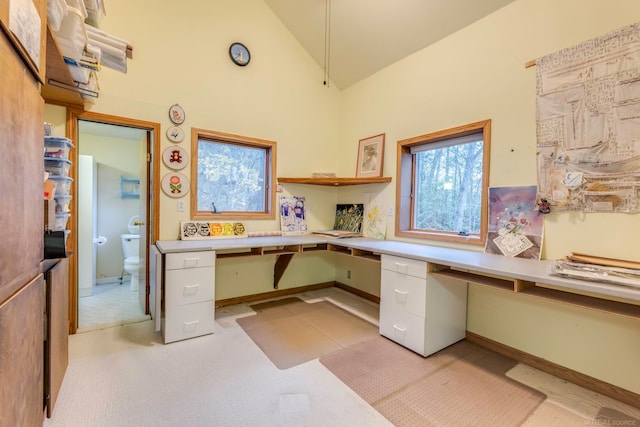 office with light colored carpet, built in desk, and high vaulted ceiling