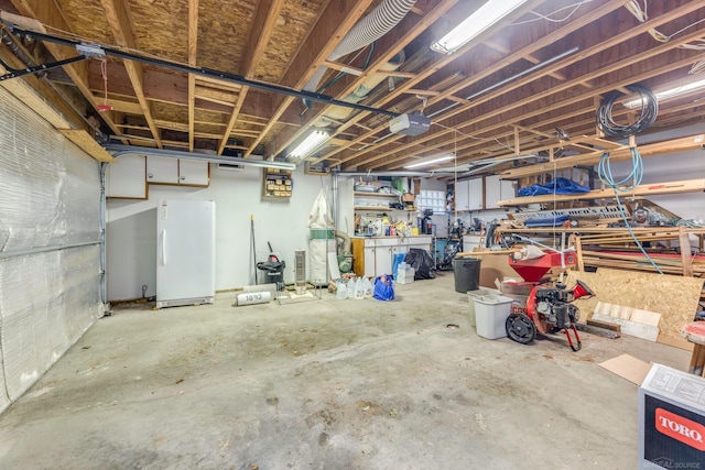 basement with a workshop area and white fridge