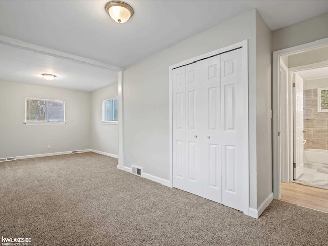 unfurnished bedroom featuring carpet flooring, ensuite bath, and a closet