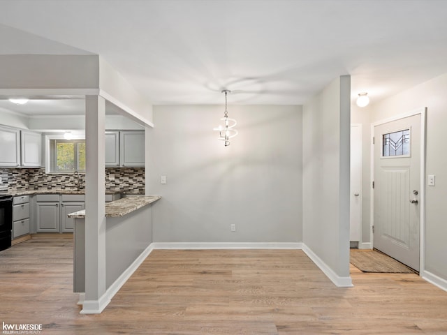 kitchen featuring gray cabinetry, pendant lighting, backsplash, black range, and light hardwood / wood-style flooring