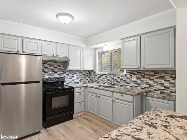 kitchen featuring stainless steel refrigerator, electric range, sink, and light stone countertops