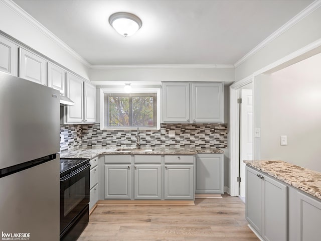 kitchen with light stone countertops, stainless steel fridge, ornamental molding, light hardwood / wood-style floors, and black / electric stove