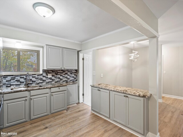 kitchen featuring gray cabinetry, sink, decorative backsplash, light wood-type flooring, and light stone counters