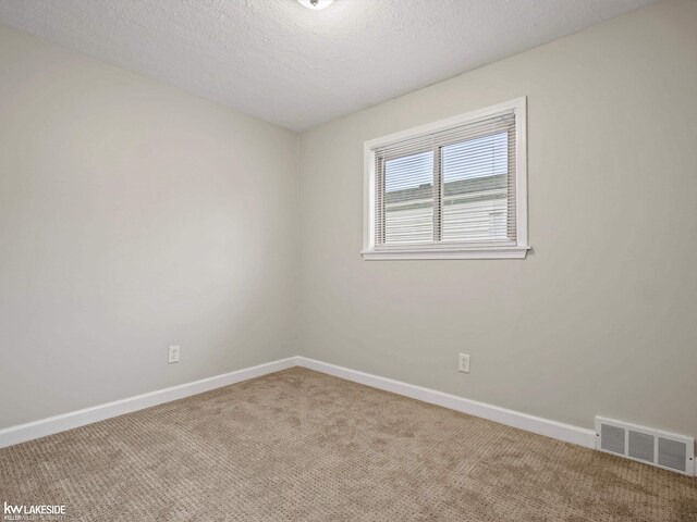 carpeted empty room featuring a textured ceiling