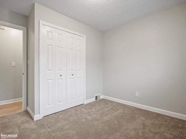 unfurnished bedroom featuring carpet flooring, a closet, and a textured ceiling