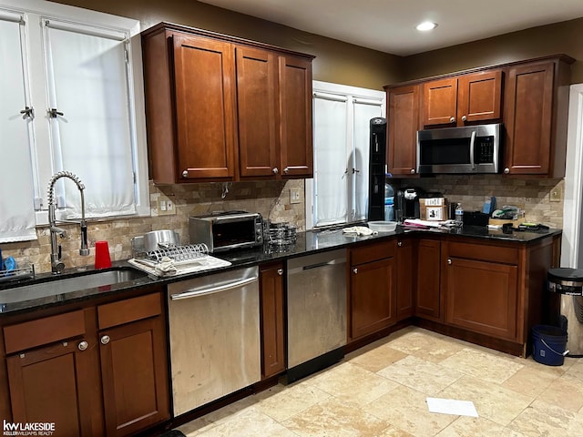 kitchen featuring stainless steel appliances, sink, decorative backsplash, and dark stone counters