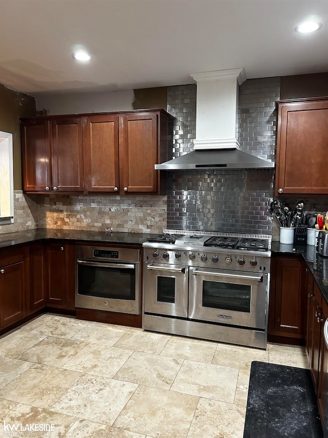 kitchen with wall chimney range hood, backsplash, and appliances with stainless steel finishes