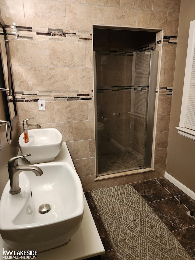 bathroom featuring dual sinks, tile walls, and a shower with shower door