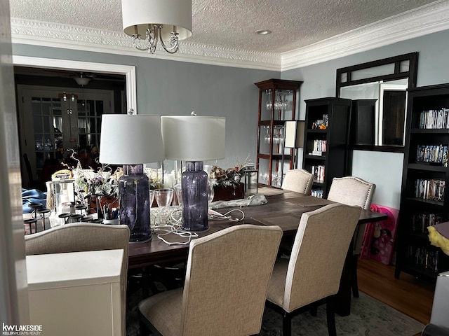 dining space with wood-type flooring, ornamental molding, and a textured ceiling