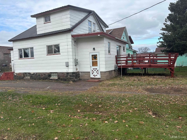 rear view of property featuring a lawn and a wooden deck