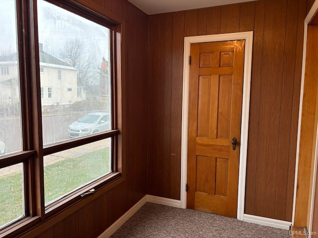 doorway with carpet flooring and wooden walls