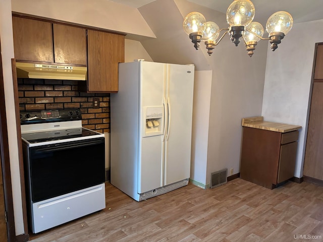 kitchen with light wood-type flooring, white appliances, decorative light fixtures, and vaulted ceiling