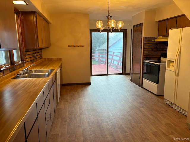 kitchen with white appliances, sink, decorative light fixtures, light hardwood / wood-style flooring, and an inviting chandelier