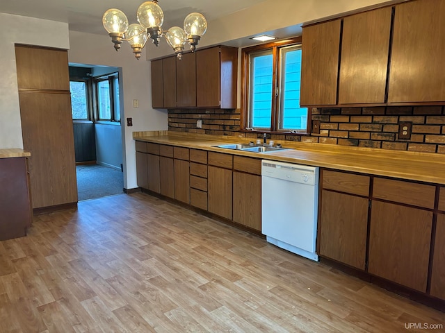 kitchen with sink, hanging light fixtures, light hardwood / wood-style flooring, white dishwasher, and decorative backsplash