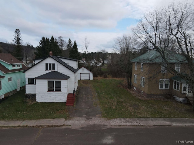 view of front of property featuring a garage, an outbuilding, and a front yard