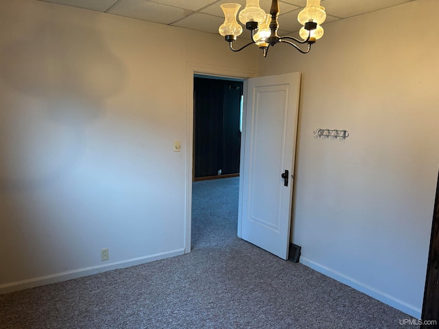 unfurnished room featuring a paneled ceiling, carpet floors, and a chandelier