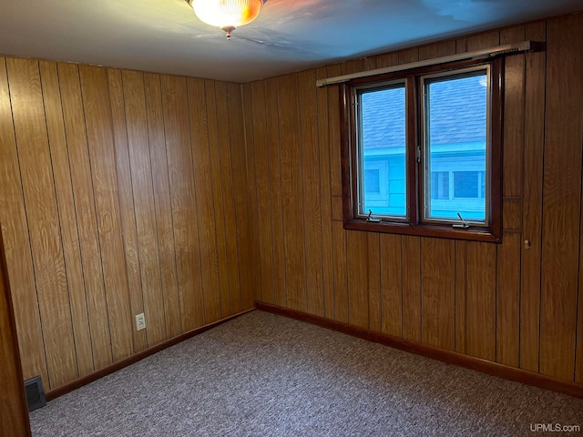 carpeted empty room with wood walls