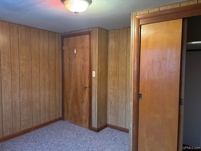 hall with wood walls and light carpet