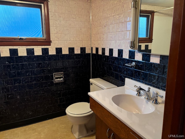 bathroom with vanity, toilet, and tile walls