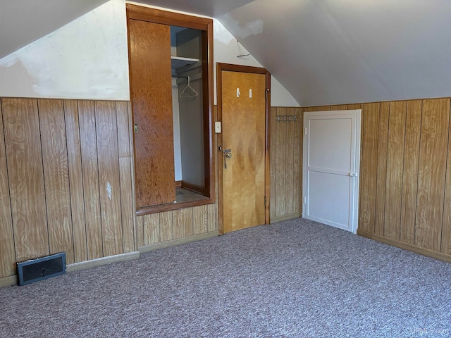 additional living space with wood walls, carpet floors, and vaulted ceiling