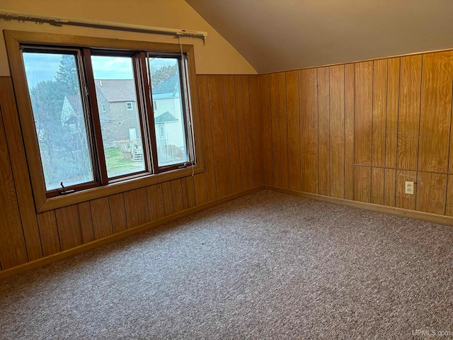 bonus room featuring carpet flooring, wooden walls, and vaulted ceiling