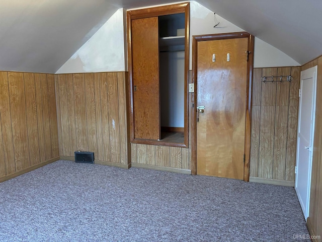 additional living space featuring carpet flooring, wood walls, and vaulted ceiling