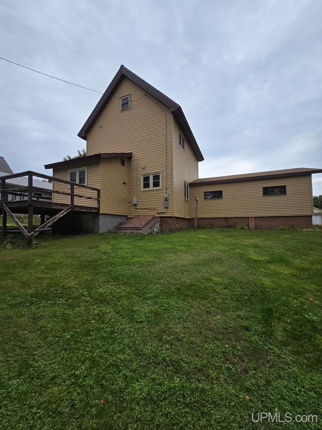 rear view of house featuring a lawn and a wooden deck