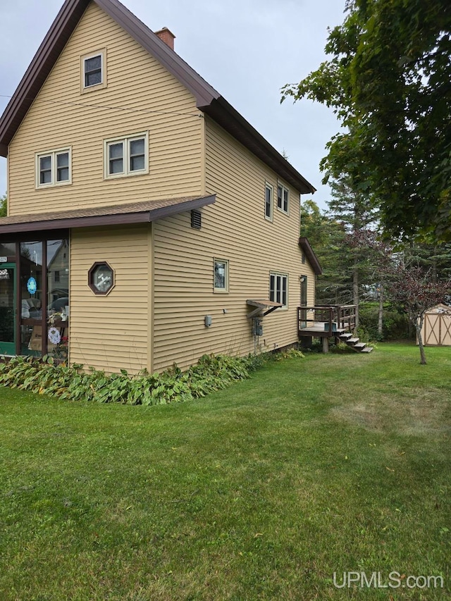 rear view of property featuring a wooden deck and a lawn