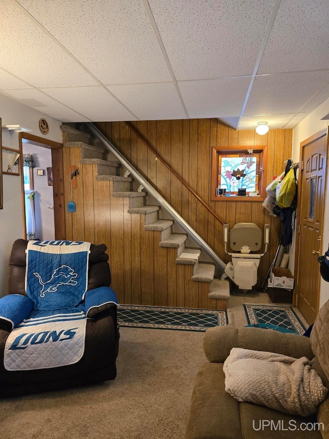 interior space with wooden walls, a drop ceiling, and carpet