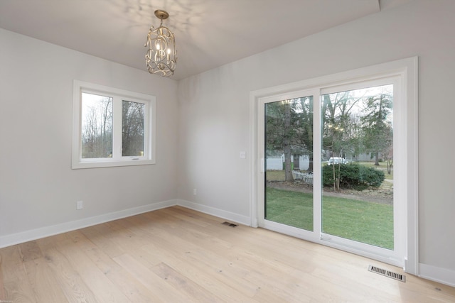 unfurnished dining area with an inviting chandelier and light wood-type flooring