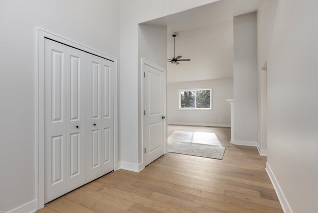 hall with light wood-type flooring and a towering ceiling