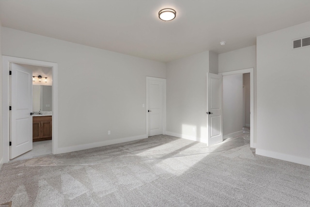 unfurnished bedroom featuring ensuite bathroom and light colored carpet