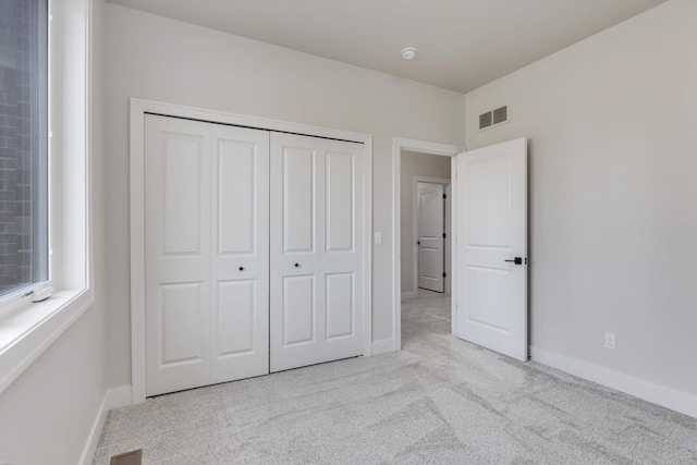 unfurnished bedroom featuring a closet and light colored carpet