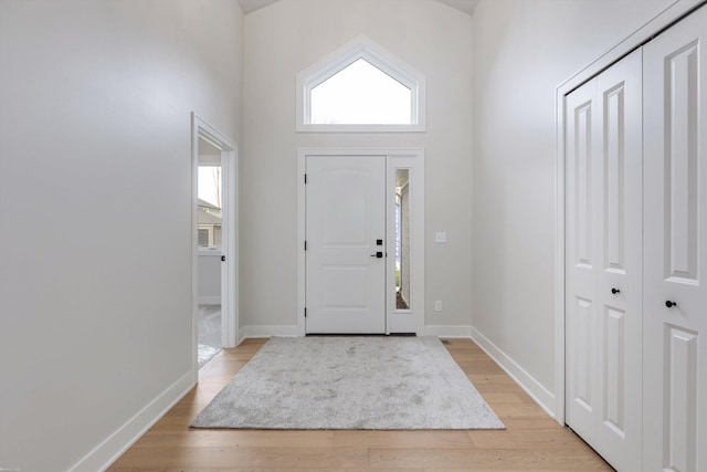 entrance foyer featuring light wood-type flooring and a towering ceiling