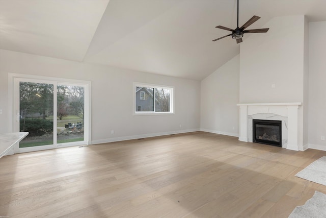 unfurnished living room featuring a high end fireplace, ceiling fan, light wood-type flooring, and high vaulted ceiling