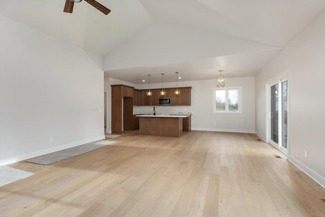 unfurnished living room featuring ceiling fan with notable chandelier, light hardwood / wood-style floors, high vaulted ceiling, and sink