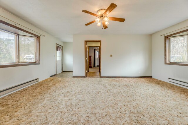 carpeted spare room with a baseboard radiator, a wealth of natural light, and ceiling fan