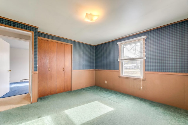 unfurnished bedroom with light colored carpet, a baseboard radiator, and a closet