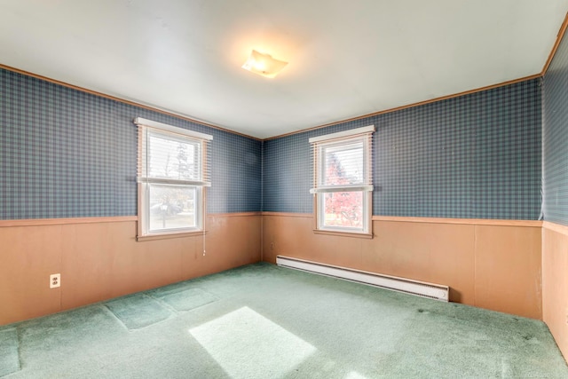 carpeted empty room with wood walls, ornamental molding, and a baseboard heating unit