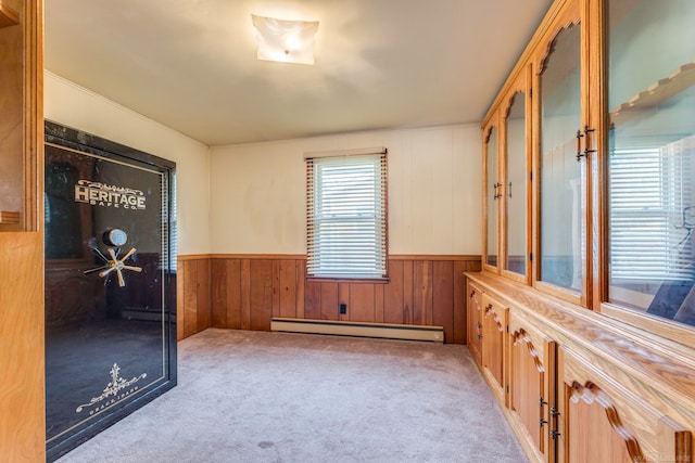 unfurnished room with wood walls, light colored carpet, and a baseboard heating unit