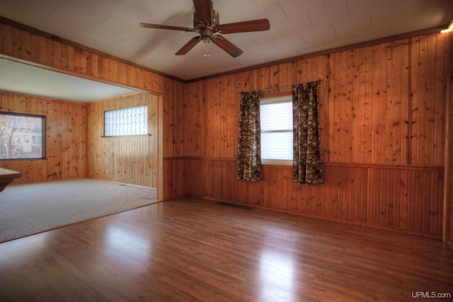 unfurnished room featuring hardwood / wood-style floors, a wealth of natural light, and wooden walls