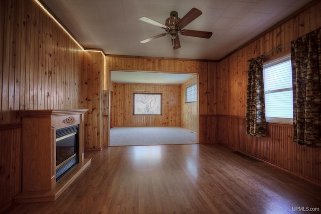 unfurnished living room with wood-type flooring, a wealth of natural light, and wooden walls