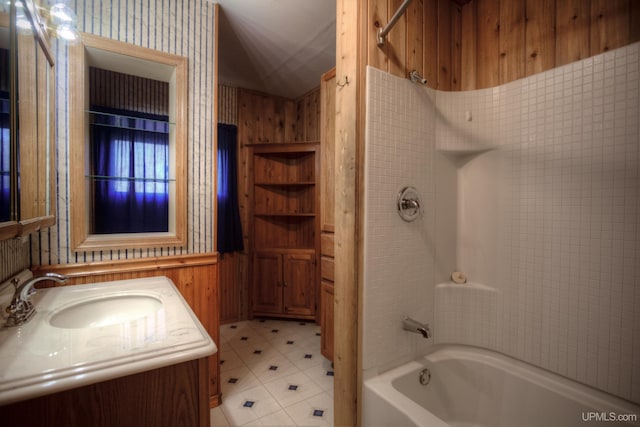 bathroom with vanity, wooden walls, and tub / shower combination