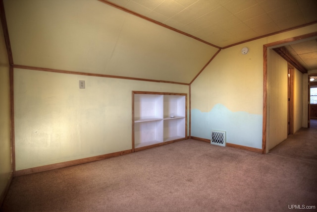 additional living space featuring built in shelves, light carpet, and vaulted ceiling