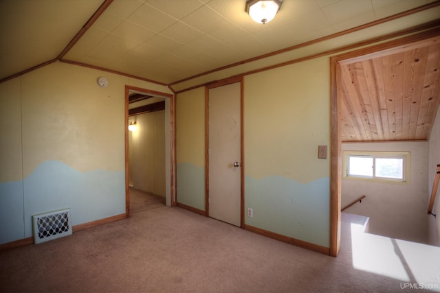 carpeted spare room with crown molding and vaulted ceiling