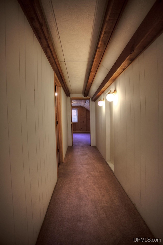 corridor featuring beamed ceiling, carpet floors, and wooden walls