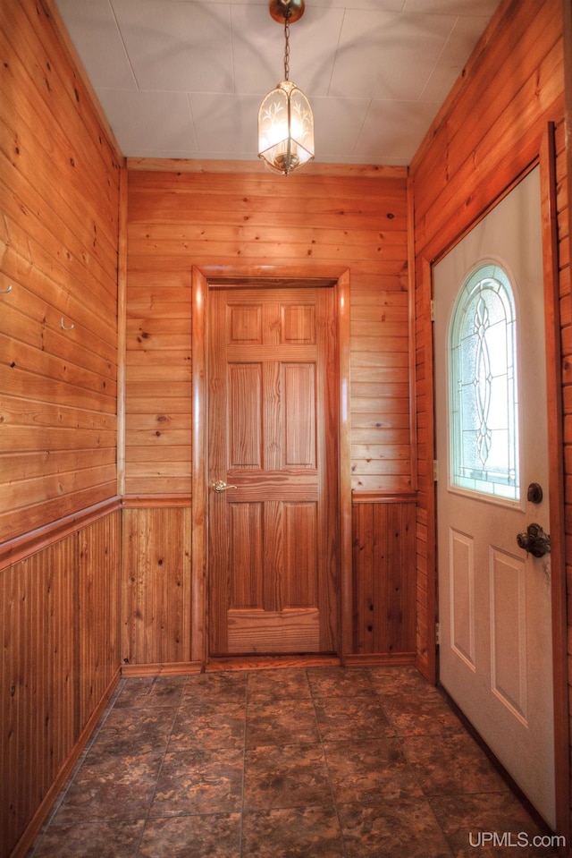 foyer entrance featuring wood walls and a notable chandelier