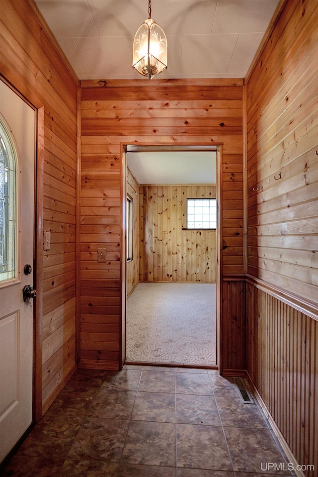 entrance foyer with wooden walls and dark carpet