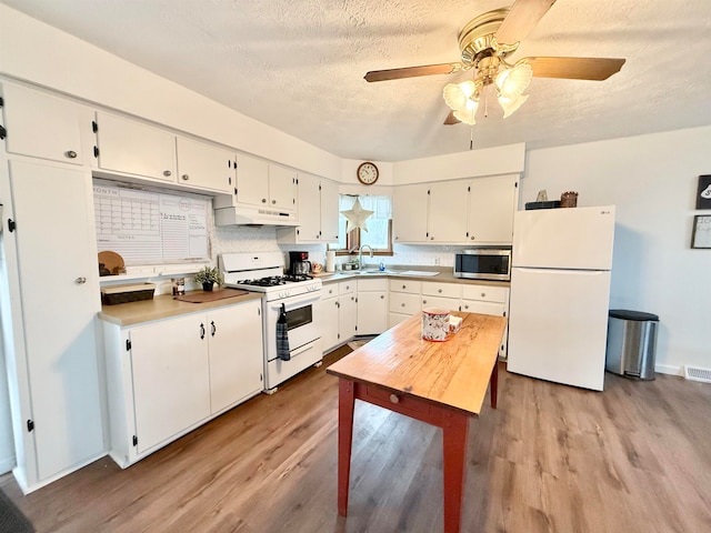 kitchen featuring sink, white cabinets, white appliances, and light wood-type flooring