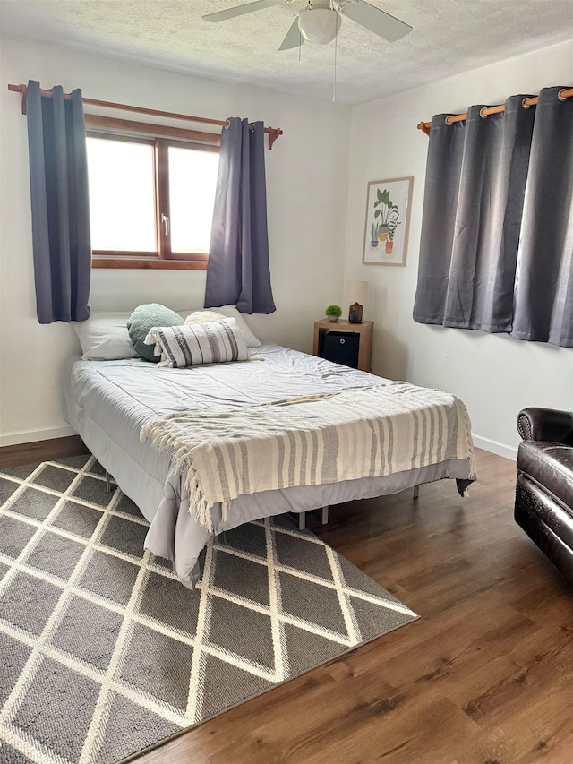 bedroom featuring a textured ceiling, ceiling fan, and dark wood-type flooring